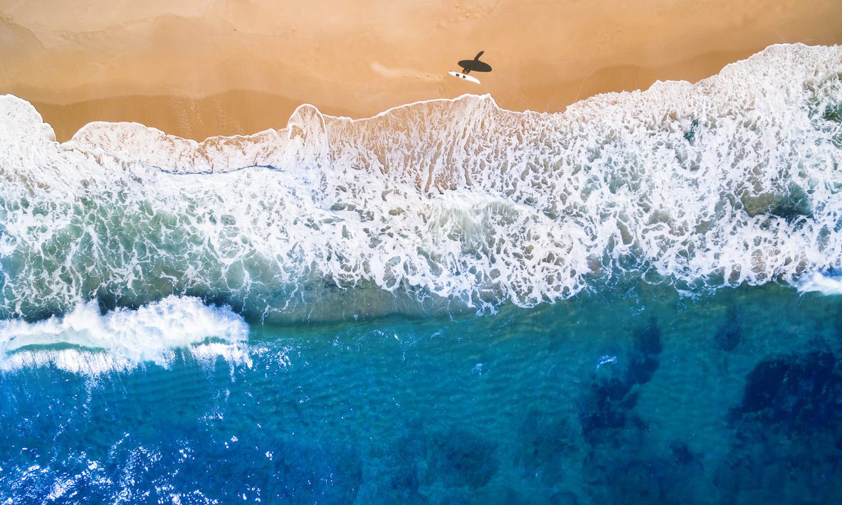 Aerial view of surfer going into the sea